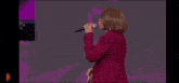 a woman in a red jacket and red pants stands on a stage