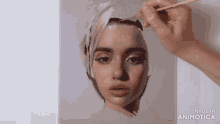 a woman is painting a woman 's face with a brush .