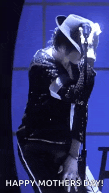 a man in a white hat is standing in front of a microphone and dancing .
