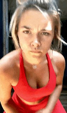 the woman is wearing a red sports bra and a red skirt .
