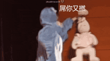 a person in a blue hoodie is standing next to a stuffed animal with chinese characters on it