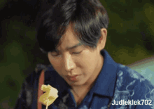 a man in a blue shirt is eating something on a skewer .