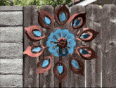 a peacock feather wind spinner is hanging on a fence