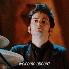 a man in a suit and tie is holding a plate and says welcome aboard