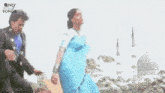 a woman in a blue dress is standing in a park .