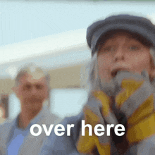 a woman wearing a hat and gloves says " over here "
