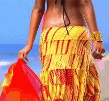 a woman in a yellow and red skirt holds a red cloth
