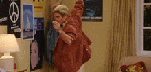 a man is dancing in a room with posters on the wall including one that says " society alliance "