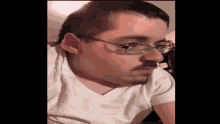 a man wearing glasses and a white shirt is looking at the camera