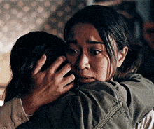a woman is hugging another woman in a dark room and the woman is crying .