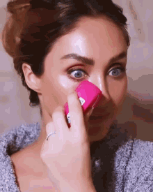a woman with a ring on her finger is holding a pink object in her hand