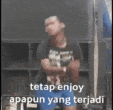 a man is dancing in front of a speaker with the words `` tetap enjoy apapun yang terjadi '' written below him .