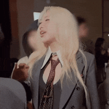 a woman wearing a suit and tie is standing in a room