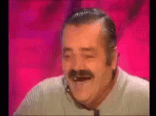 a man with a mustache is laughing with his eyes closed .