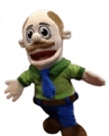 a puppet with a mustache and a green shirt and tie is standing on a white background .