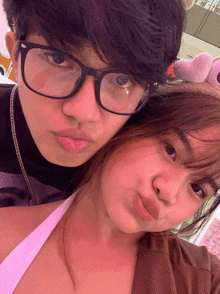 a boy wearing glasses is standing next to a girl