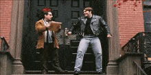 a man in a leather jacket is standing on a set of stairs talking to another man