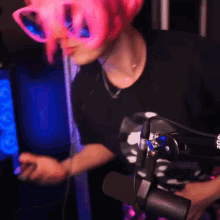 a person wearing a pink wig and sunglasses stands in front of a microphone