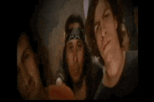 a man holding a guitar next to another man with a bandana on his head