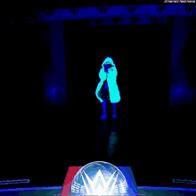 a person in a glow in the dark coat is standing in front of a glowing w logo