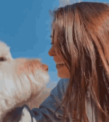 a woman with long hair is petting a small white dog