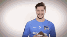 a man in a blue shirt with the number 5 on it is smiling