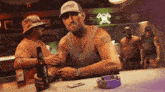 a man sitting at a bar with a bottle of budweiser in front of him