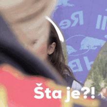 a woman stands in front of a purple sign that says " sta je "