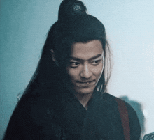 a man with long hair is wearing a black shirt and a ponytail