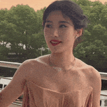 a woman wearing a strapless dress and a feather necklace