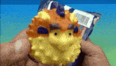 a person is holding a toy in their hand that looks like a puffer fish .