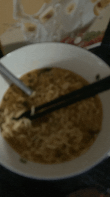 a close up of a bowl of noodles with chopsticks in it