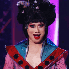 a woman in a costume with flowers in her hair and red lips