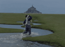a person is walking through a stream with a rope around their waist