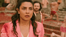 a woman in a pink jacket is standing in front of a crowd of people .