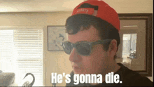 a man wearing sunglasses and a red hat with the words he 's gonna die