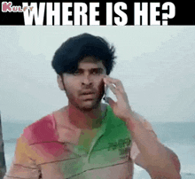 a man is talking on a cell phone in front of the ocean .