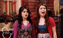 two girls are standing next to each other with their mouths open and looking surprised .