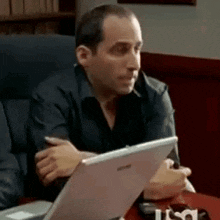 a man is sitting at a desk with a laptop and a usa logo on the table .