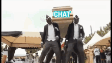 two men in tuxedos are carrying a coffin on their shoulders with the word chat above them
