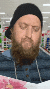 a man with a beard wearing a black hat is looking at a card