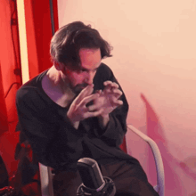 a man sitting in front of a microphone with his hands on his face