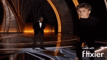 a man in a tuxedo is standing on a stage with the words made with flixier