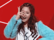 a woman wearing a blue fur coat and a white shirt with the letter s on it