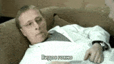 a man in a lab coat is laying on a couch talking to another man in a foreign language .