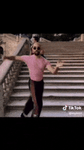 a man in a pink shirt is dancing on a set of steps