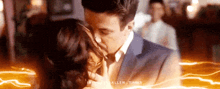 a man in a suit and tie is kissing a woman in a dark room .