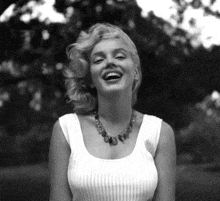 a black and white photo of a woman wearing a white tank top and a necklace