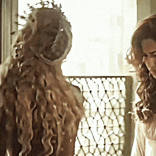 a woman with a crown on her head stands next to a woman with long hair