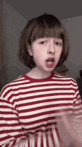 a girl wearing a red and white striped shirt is making a funny face